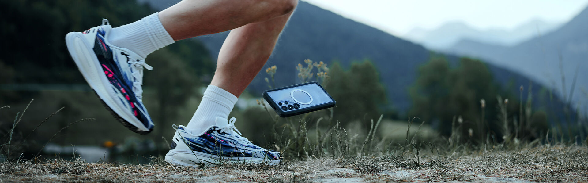 Person wearing running shoes with a phone displaying a map in a natural setting